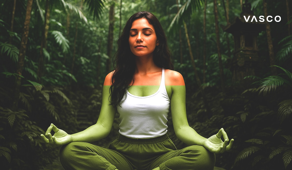 Egy nő békésen meditál lótuszülésben, egy balinéz erdő buja növényzetével körülvéve.