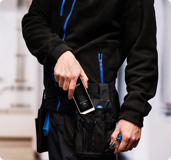 Munkaruhás férfi előhúz egy Vasco Translator V4-et a szerszámos övéről.