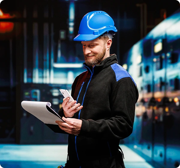 Két férfi beszélget egymással; a teherautó-sofőr egy Vasco Translator V4-et tart a kezében, a szemben álló személy, aki raktári munkásnak tűnik, dokumentumokat tart. A Vasco Translator segítségével kommunikálnak.